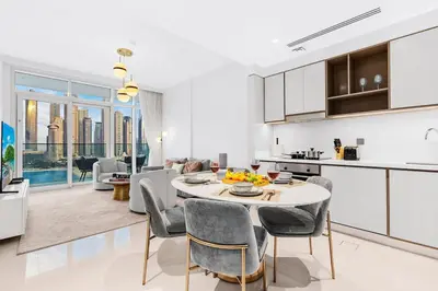 a kitchen and living room with a table and chairs at Sea View 2BR Near Beach Marina Walk & Dining Spots in Dubai