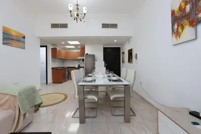a dining room and kitchen with a table and chairs at Cozy 1BR Apartment in Lolena Tower, JVC - Allsopp & Allsopp in Dubai