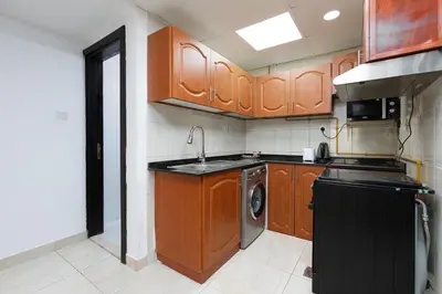 a kitchen with wooden cabinets and a sink and a dishwasher at Cozy 1BR Apartment in Lolena Tower, JVC - Allsopp & Allsopp in Dubai