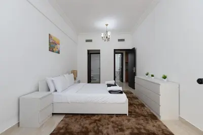 a white bedroom with a white bed and a mirror at Cozy 1BR Apartment in Lolena Tower, JVC - Allsopp & Allsopp in Dubai