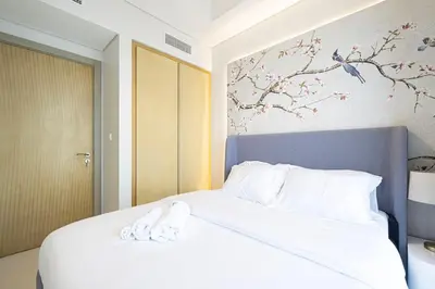 a bedroom with a bed with white sheets and birds on the wall at UrbanHomes - Luxury and Cozy 3BDR Apartment in Business Bay Canal View in Dubai