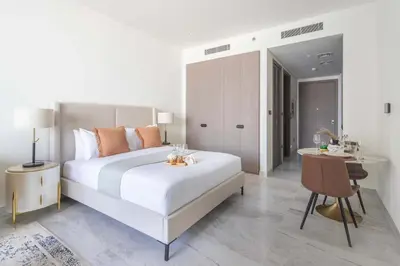 a white bedroom with a large bed and a desk at Frank Porter - Peninsula Five in Dubai