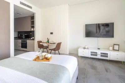 a bedroom with a bed and a table and a kitchen at Frank Porter - Peninsula Five in Dubai