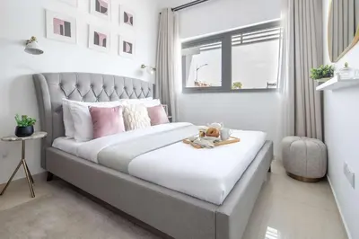 a bedroom with a bed with pink pillows and a window at Frank Porter - Avencia 44 in ‘Ūd al Bayḑāʼ