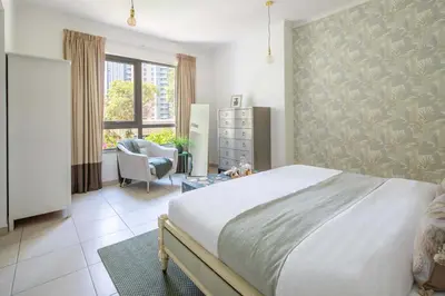 a bedroom with a bed and a chair and a window at Frank Porter - The Residences 5 in Dubai
