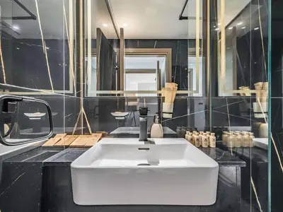a bathroom with a white sink and black walls at TRPS - Binghatti Emerald, Jumeirah Village Circle - Luxury 1BR Haven in Dubai
