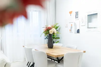 a dining room table with white chairs and a vase with flowers at Veluxa - Renovated 1BHK next to Golf in Dubai