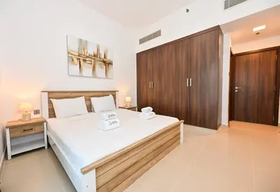 a bedroom with a large bed and a wooden cabinet at Stylish 1BR Apartment - Central Location in JVC - Balcony - Holiday Boulevard in Dubai