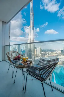 a balcony with a table and chairs and a view of a city at Venetian - Refined 2BR at Grande Tower, Burj & Fountain views in Dubai