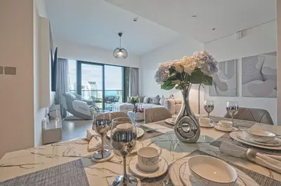 a dining room with a table with a vase of flowers at Venetian - Refined 2BR at Grande Tower, Burj & Fountain views in Dubai