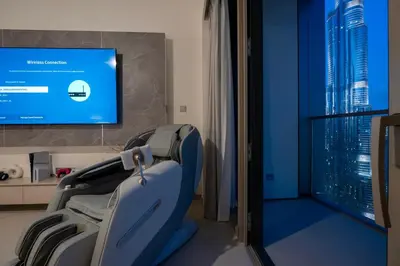 a hospital room with a chair and a flat screen tv at Venetian - Refined 2BR at Grande Tower, Burj & Fountain views in Dubai