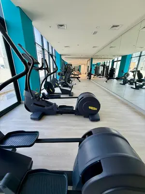 a gym with rows of treadmills and elliptical machines at Azizi Rivera 33 in Dubai