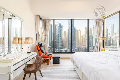 a bedroom with a bed and a desk and a large window at Nomad Retreats- Silverene tower Marina view in Dubai