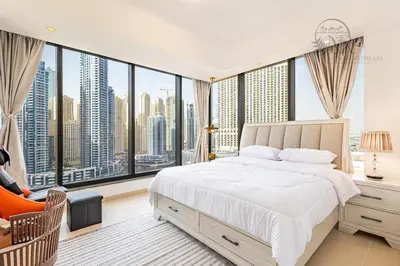 a bedroom with a bed and large windows at Nomad Retreats- Silverene tower Marina view in Dubai