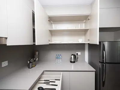 a white kitchen with white cabinets and a refrigerator at Beachfront Family Entire Unit in Dubai Ras Al-Khor in Dubai