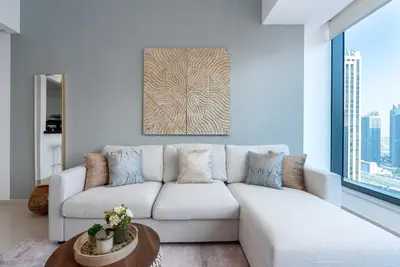 a white couch in a living room with a large window at Silverene Tower - One Bedroom By Home Of Choice in Dubai