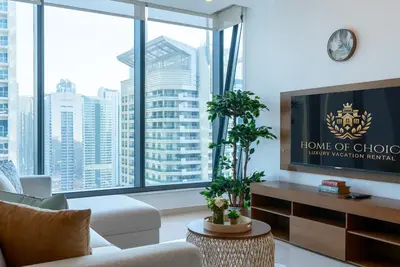 a living room with a couch and a large window at Silverene Tower - One Bedroom By Home Of Choice in Dubai