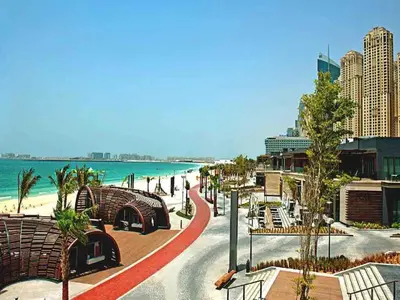 a view of a beach with benches and the ocean at Silverene Tower - One Bedroom By Home Of Choice in Dubai