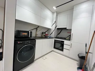 a kitchen with white cabinets and a washer at Luxury - Burj Khalifa View - Private Jacuzzi in Dubai