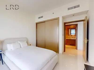 a bedroom with a white bed and a wooden door at Waterfront 1 Bedroom Apartment - Private Beach - Emaar Beachfront in Dubai