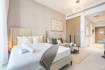 a bedroom with a large white bed and a living room at Near Dubai Miracle Garden Studio with Community Views Balcony, Legacy by Sunrise, Arjan-Dubailand by Deluxe Holiday Homes in Dubai