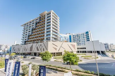a large building in a city with a street at Near Dubai Miracle Garden Studio with Community Views Balcony, Legacy by Sunrise, Arjan-Dubailand by Deluxe Holiday Homes in Dubai