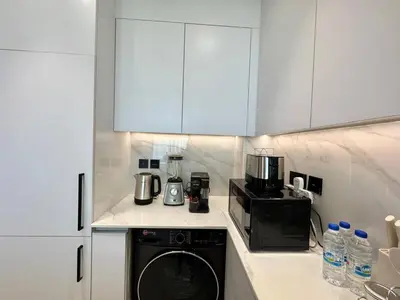 a kitchen with white cabinets and a washer and a microwave at Bright & Modern 1br In Jvc Pool Free Parking in Dubai