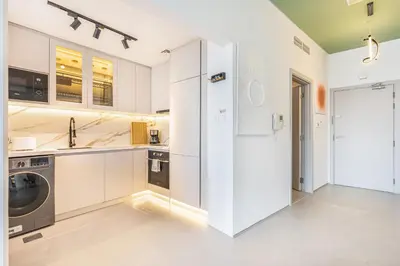 a kitchen with white cabinets and a washer and dryer at Premium & Cozy Home in the Heart of Sports City in Dubai