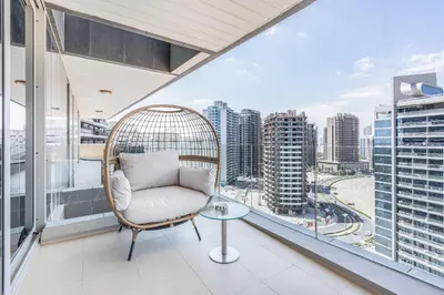 a chair on a balcony with a view of a city at Premium & Cozy Home in the Heart of Sports City in Dubai