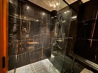 a bathroom with a shower with black tiled walls at Disalvo Smart and Luxury Studio in Dubai