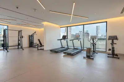 a gym with treadmills and ellipticals in a room with windows at StayShort - Sleek Studio in The Ivy Tower, JVT in Dubai