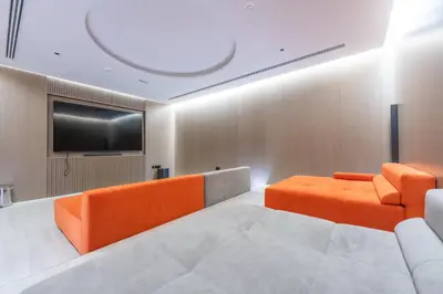 a room with orange furniture and a flat screen tv at StayShort - Sleek Studio in The Ivy Tower, JVT in Dubai