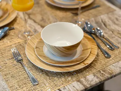 a table with a cup and plates and forks and spoons at Crown Jewel 2 Bedroom Apartments I Iconic Burj Khalifa and Fountain Views I Free Parking, Gym, Pool, Wi-Fi and PS5 I by Skyline Serenity in Dubai