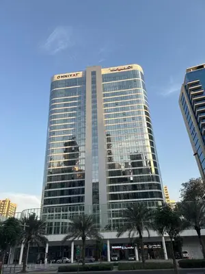 a tall glass building with palm trees in front of it at The Pad by Omniyat in Dubai