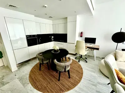 a living room with a table and chairs and a desk at The Pad by Omniyat in Dubai