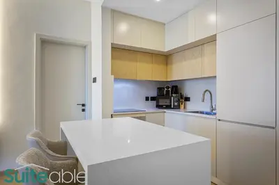 a white kitchen with a white counter and a sink at Stylish 1 Bedroom near metro station in JLT in Dubai