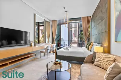 a living room with a couch and a tv at Vibrant & Exclusive Pool View Studio in Autograph in Dubai