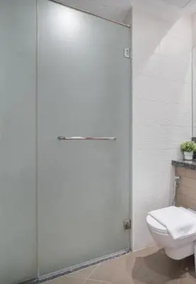 a bathroom with a toilet and a glass shower door at Business Bay Mahek Holiday Home in Dubai