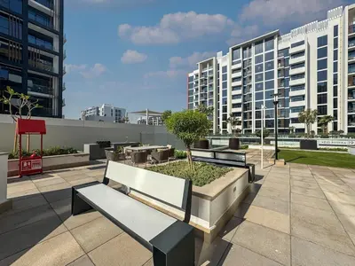 two benches sitting on a patio with buildings at Sleek Studio in Azizi Riviera Modern and Cozy Stay in Dubai
