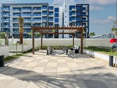 a pergola in front of a large building at Sleek Studio in Azizi Riviera Modern and Cozy Stay in Dubai