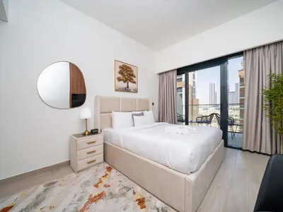 a white bedroom with a large bed and a mirror at Sleek Studio in Azizi Riviera Modern and Cozy Stay in Dubai