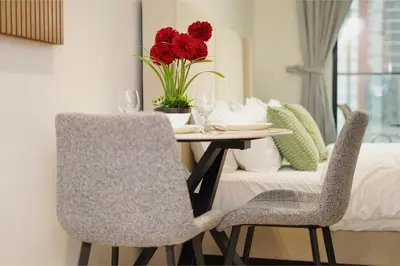 a table with two chairs and a vase with red flowers at PurityStaysDXB in Dubai