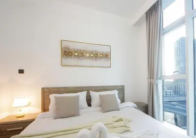a bedroom with a bed with white sheets and a window at Luxury 2BR Apartment in Urban Oasis by Missoni in Dubai