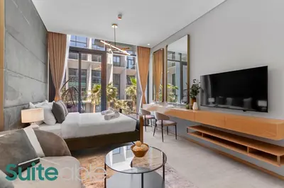 a living room with a couch and a tv at Aesthetic Studio with Stunning Pool View in JVC in Dubai