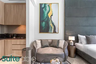 a living room with a couch and a chair at Aesthetic Studio with Stunning Pool View in JVC in Dubai