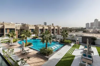 an overhead view of a pool with palm trees and buildings at Modern Studio Apartment JVC in Dubai