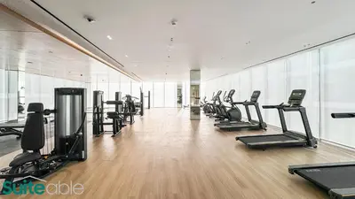 a gym with a row of treadmills and machines at Sophisticated 1 Bedroom in Binghatti Galaxy JVC in Dubai