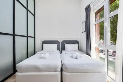 two beds in a room with a window at Studio Haven with Pool, Tennis and Kid's Playground in Dubai
