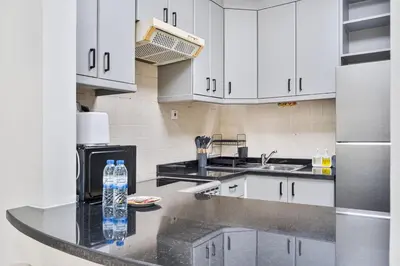 a kitchen with white cabinets and a counter with water bottles at Studio Haven with Pool, Tennis and Kid's Playground in Dubai