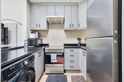 a kitchen with white cabinets and a stainless steel refrigerator at Studio Haven with Pool, Tennis and Kid's Playground in Dubai
